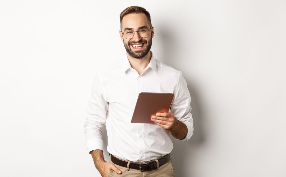 Confident business man holding digital tablet and smiling, standing against white background